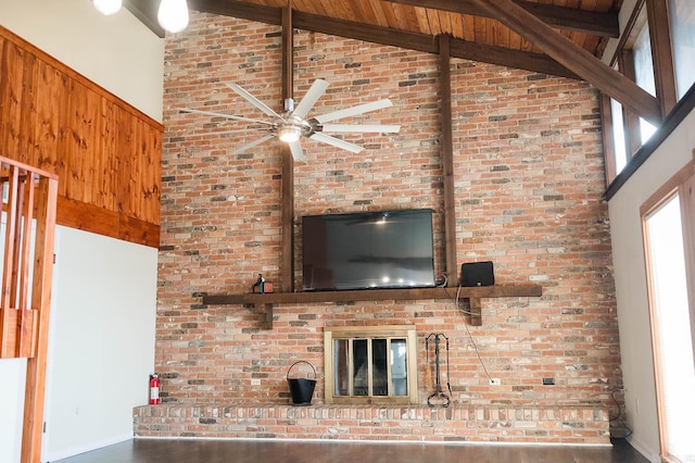 unfurnished living room featuring beam ceiling, ceiling fan, high vaulted ceiling, a brick fireplace, and dark hardwood / wood-style floors