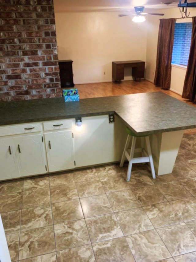 kitchen with white cabinetry, kitchen peninsula, and ceiling fan