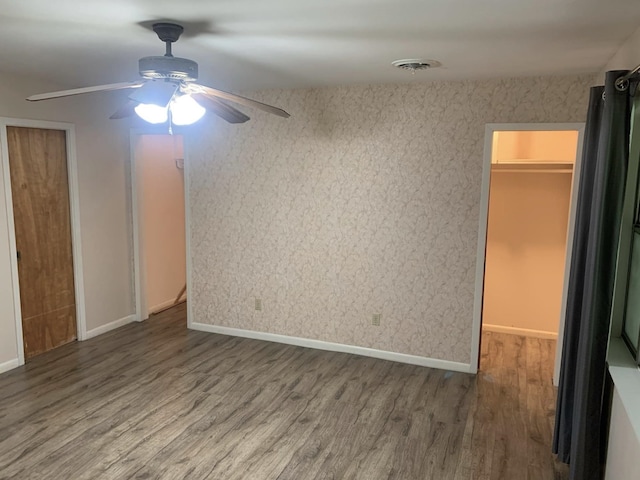 unfurnished bedroom with a spacious closet, ceiling fan, and hardwood / wood-style flooring