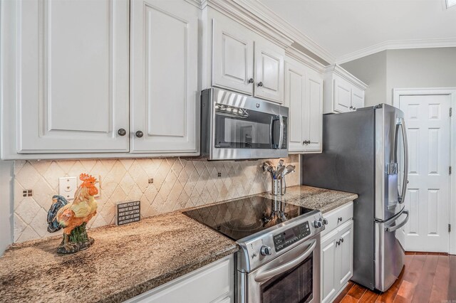 kitchen with stone countertops, ornamental molding, white cabinets, light wood-type flooring, and appliances with stainless steel finishes