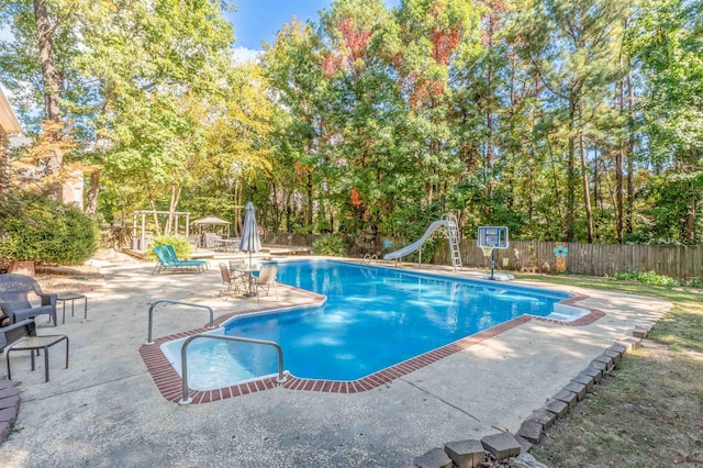 view of swimming pool with a patio area and a water slide