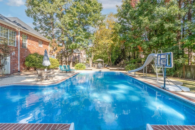 view of swimming pool with a patio and a water slide