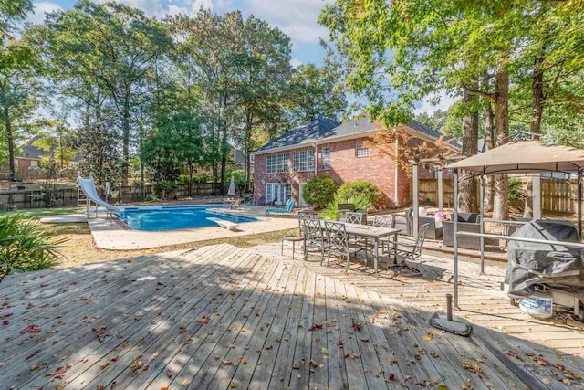 view of swimming pool featuring a gazebo, a water slide, a deck, and a diving board