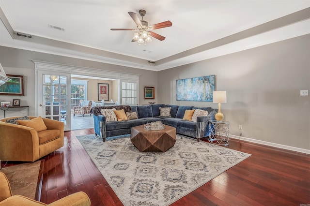 living room with crown molding, dark hardwood / wood-style floors, a tray ceiling, and ceiling fan