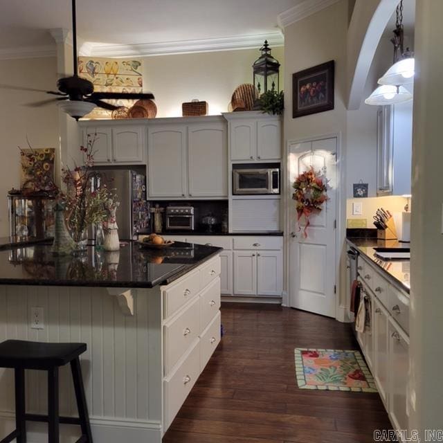 kitchen with appliances with stainless steel finishes, ornamental molding, dark hardwood / wood-style floors, and white cabinets