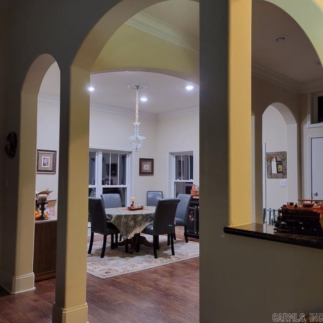 dining area featuring dark wood-type flooring, crown molding, and an inviting chandelier