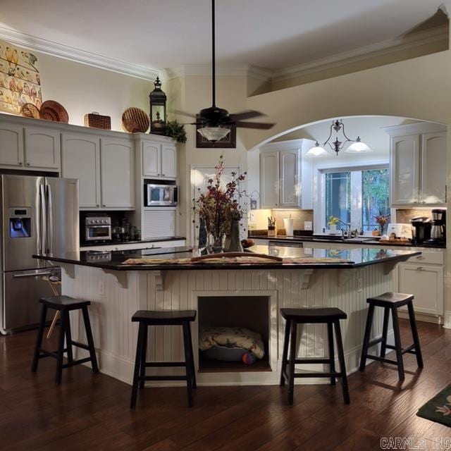 kitchen with appliances with stainless steel finishes, a breakfast bar, white cabinets, and dark hardwood / wood-style flooring