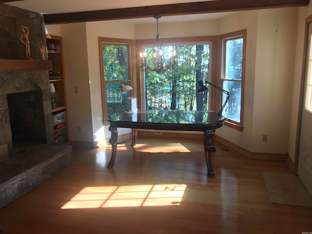 unfurnished dining area with a chandelier, wood-type flooring, a fireplace, and a wealth of natural light