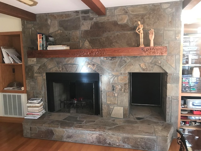 details featuring a stone fireplace, beam ceiling, and wood-type flooring