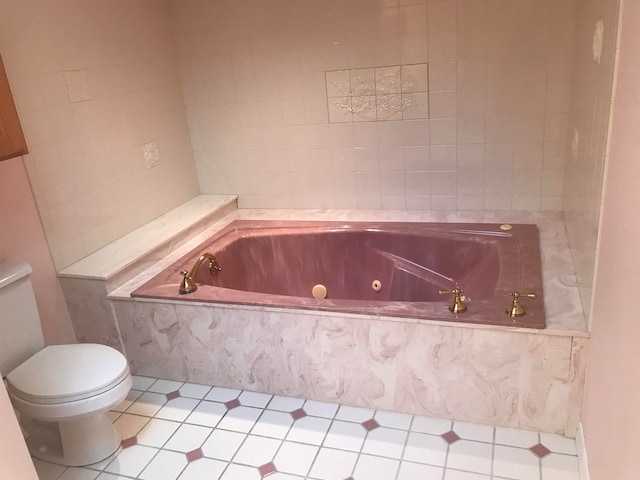 bathroom featuring toilet, tiled bath, and tile patterned floors