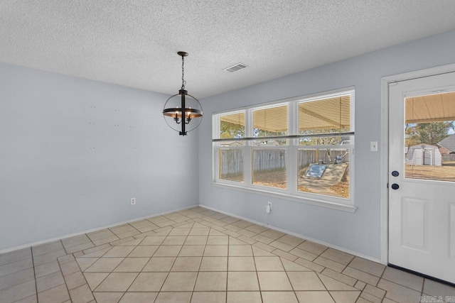 unfurnished dining area featuring a healthy amount of sunlight, a textured ceiling, and a chandelier