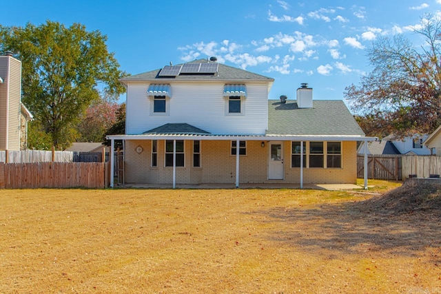 back of house with a patio area, solar panels, and a lawn