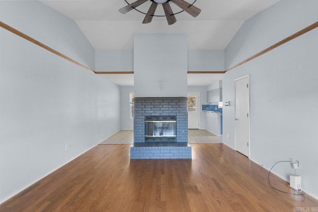 unfurnished living room featuring light hardwood / wood-style floors, lofted ceiling, a fireplace, and ceiling fan