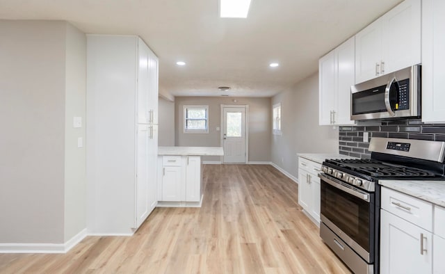 kitchen with white cabinets, light hardwood / wood-style floors, and stainless steel appliances