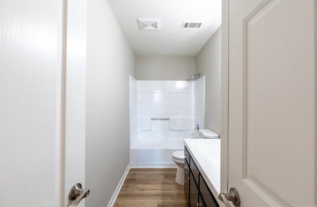 full bathroom featuring washtub / shower combination, wood-type flooring, toilet, and vanity