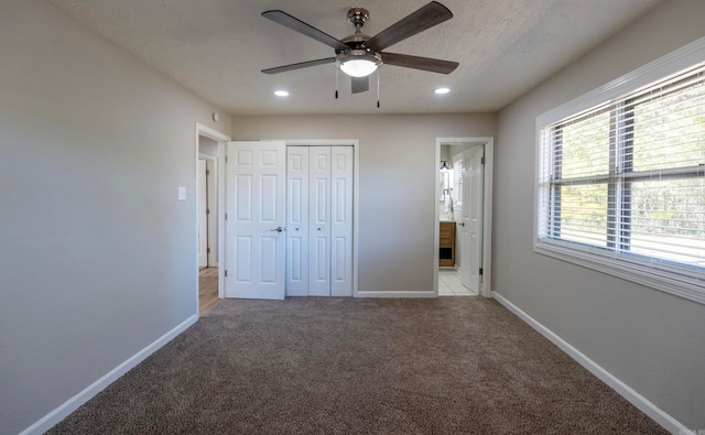 unfurnished bedroom featuring connected bathroom, a textured ceiling, light colored carpet, and ceiling fan