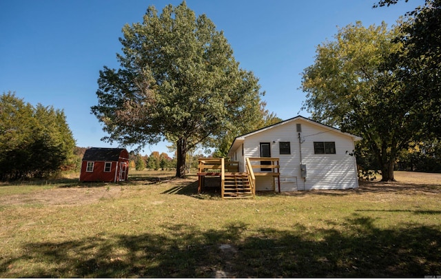 back of house with a lawn, a storage unit, and a deck