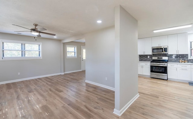 kitchen featuring tasteful backsplash, stainless steel appliances, white cabinetry, light hardwood / wood-style floors, and ceiling fan