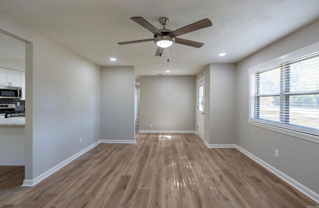 spare room featuring a textured ceiling, light hardwood / wood-style floors, and ceiling fan