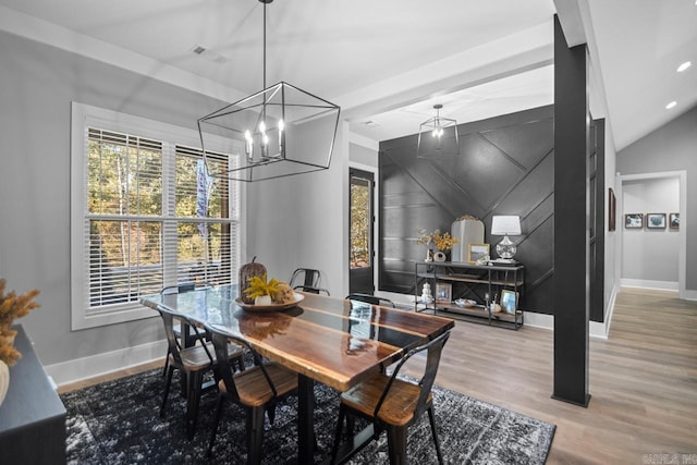 dining area with lofted ceiling, hardwood / wood-style floors, and a notable chandelier