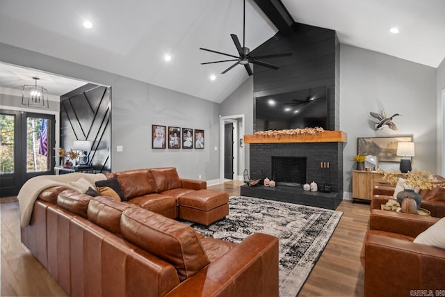 living room with beam ceiling, ceiling fan, high vaulted ceiling, light wood-type flooring, and a fireplace