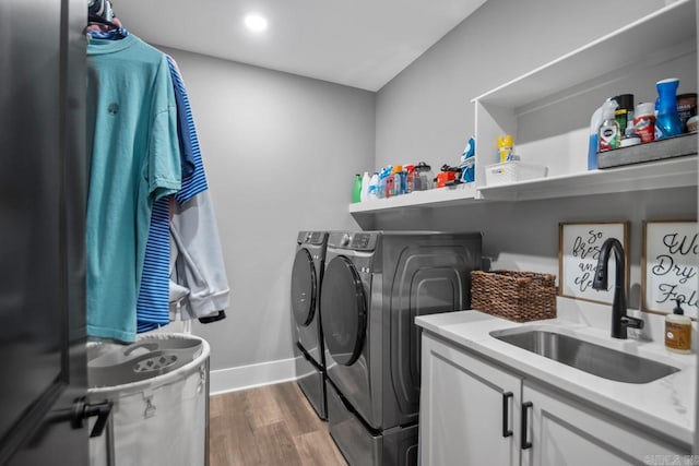 washroom with washer and dryer, hardwood / wood-style flooring, cabinets, and sink