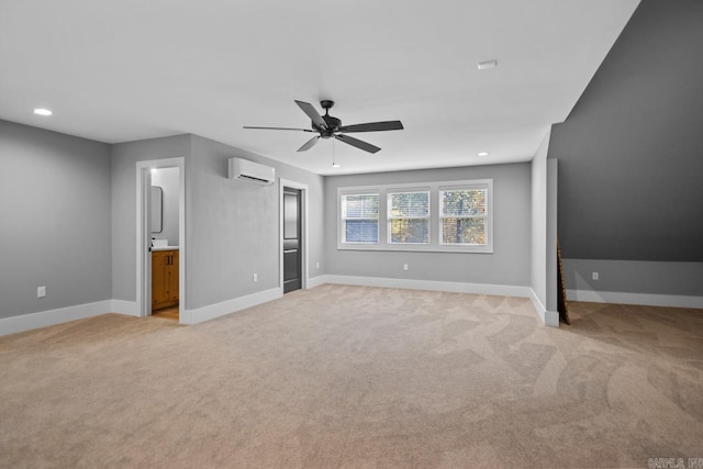 unfurnished bedroom with ensuite bath, a wall mounted air conditioner, light colored carpet, and ceiling fan