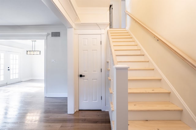 stairway with ornamental molding and hardwood / wood-style floors