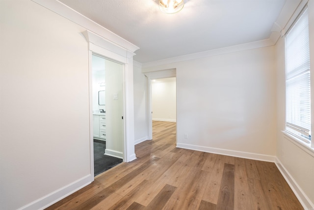 empty room with hardwood / wood-style flooring and ornamental molding