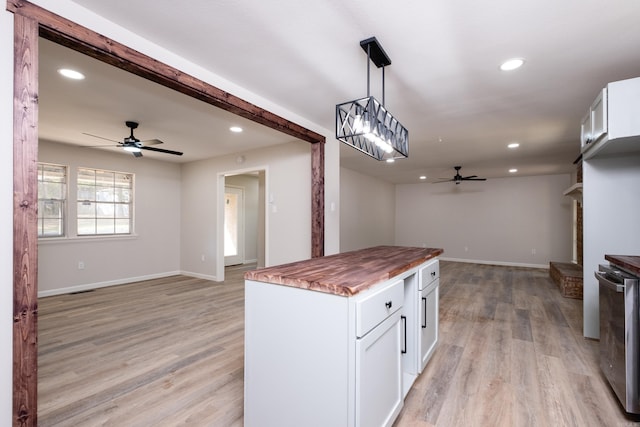 kitchen with white cabinets, light wood-type flooring, hanging light fixtures, ceiling fan, and wooden counters