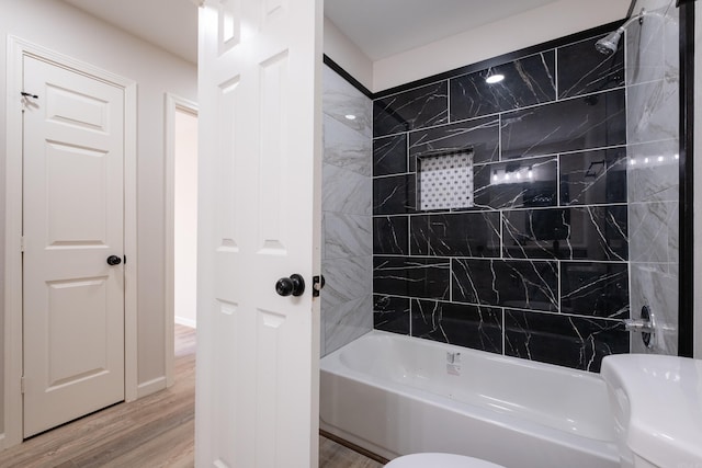 bathroom featuring toilet, tiled shower / bath, and hardwood / wood-style flooring