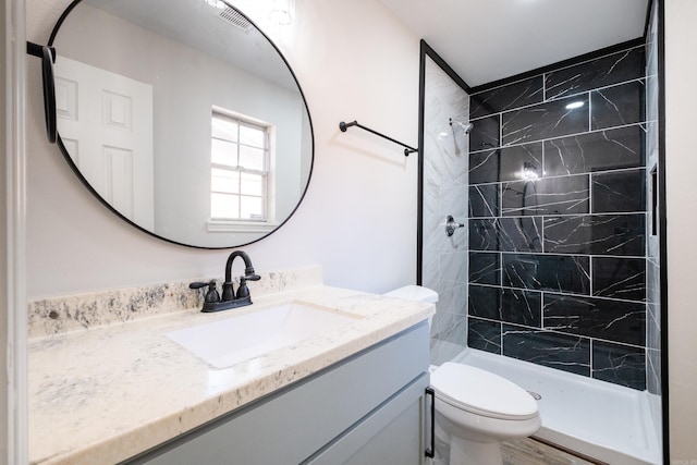 bathroom featuring vanity, tiled shower, and toilet