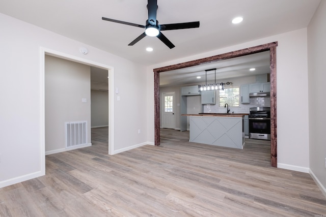 unfurnished living room featuring sink, light hardwood / wood-style floors, and ceiling fan