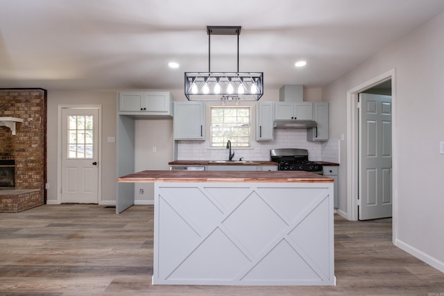 kitchen with black gas stove, light hardwood / wood-style flooring, sink, pendant lighting, and butcher block countertops