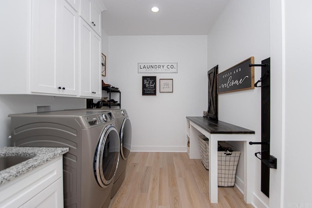 laundry area with washing machine and dryer, light hardwood / wood-style floors, and cabinets