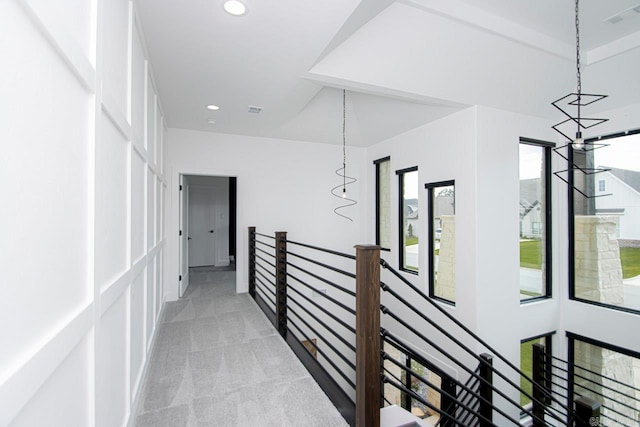 hallway with light carpet and an inviting chandelier