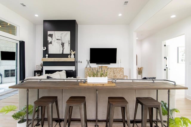 kitchen with light hardwood / wood-style flooring, a fireplace, and a kitchen breakfast bar