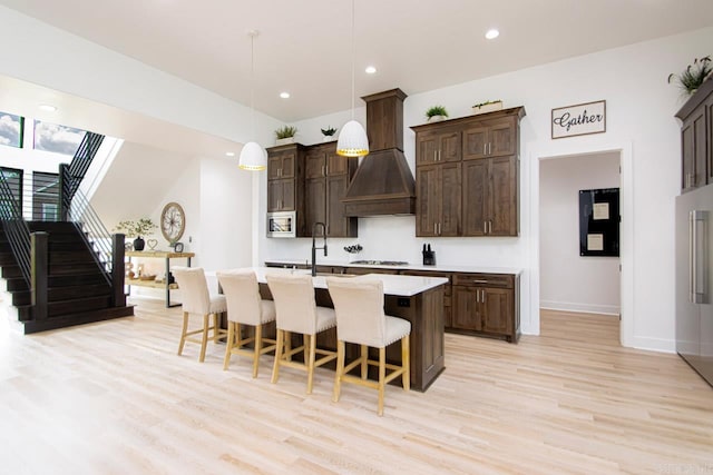 kitchen featuring dark brown cabinetry, hanging light fixtures, and light wood-type flooring