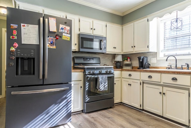 kitchen featuring tasteful backsplash, appliances with stainless steel finishes, sink, white cabinets, and light hardwood / wood-style flooring