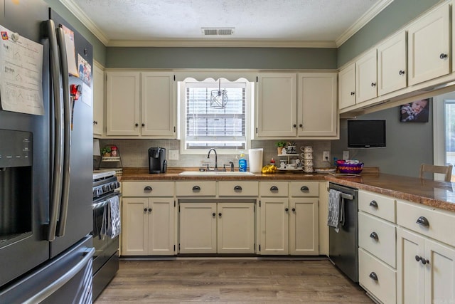 kitchen with appliances with stainless steel finishes, crown molding, hardwood / wood-style floors, and a wealth of natural light