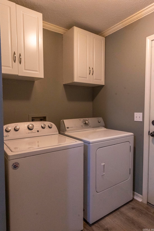 laundry room with a textured ceiling, ornamental molding, cabinets, and dark hardwood / wood-style flooring