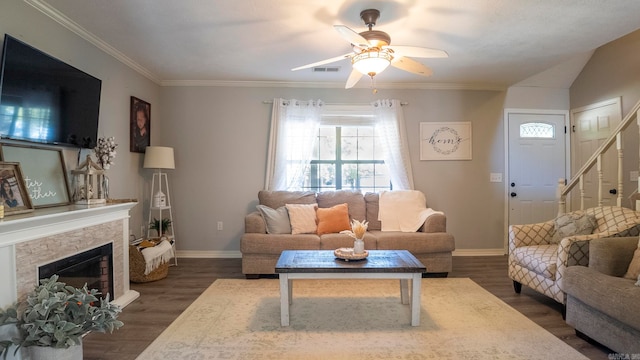 living room with ceiling fan, dark hardwood / wood-style flooring, vaulted ceiling, a fireplace, and crown molding