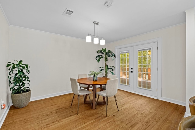 dining room featuring french doors, ornamental molding, and light wood-type flooring