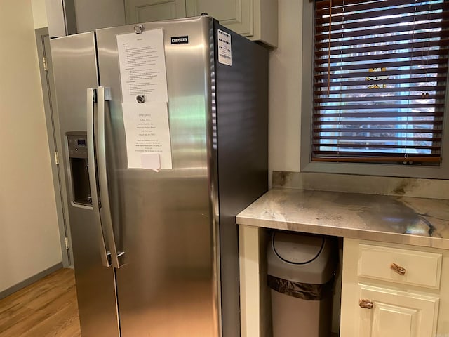 kitchen with light hardwood / wood-style floors and stainless steel fridge with ice dispenser