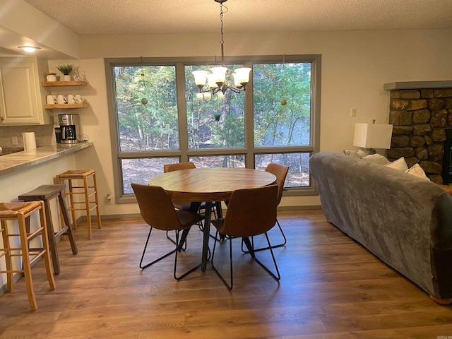 dining area featuring light hardwood / wood-style floors, an inviting chandelier, a textured ceiling, and a wealth of natural light