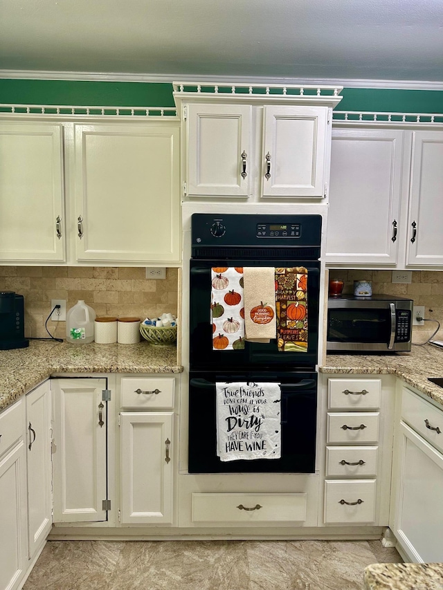 kitchen with light stone counters, ornamental molding, black double oven, and white cabinets