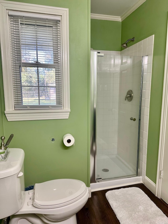 bathroom with a shower with door, toilet, ornamental molding, and hardwood / wood-style floors