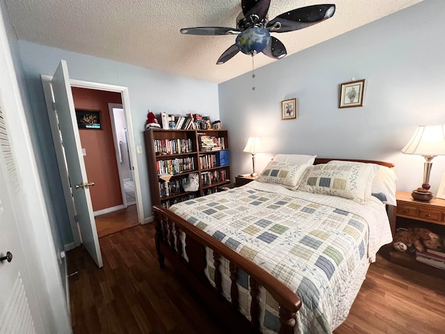 bedroom featuring dark wood-type flooring, a textured ceiling, and ceiling fan