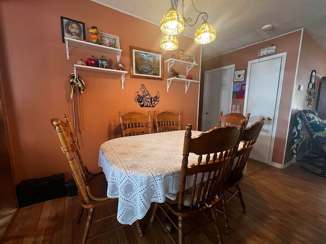 dining area with dark wood-type flooring and a textured ceiling