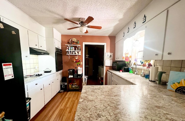 kitchen with decorative backsplash, black appliances, white cabinets, and light hardwood / wood-style flooring